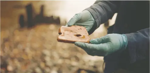  ??  ?? Lara Maiklem holds a piece of Roman roof tile. A common find, but she looks for those with an interestin­g story.