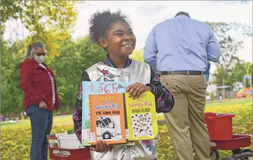  ?? Photos by Lori Van Buren / Times Union ?? Azayvia Rivera, 8, of Albany shows her father books she picked out Monday from the RED Bookshelf at Black Lives Matter Park in Albany's West Hill neighborho­od. The park was formerly known as Livingston Park.