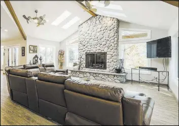  ??  ?? The family room has high, wood-beamed ceiling, skylights and a river rock fireplace.
