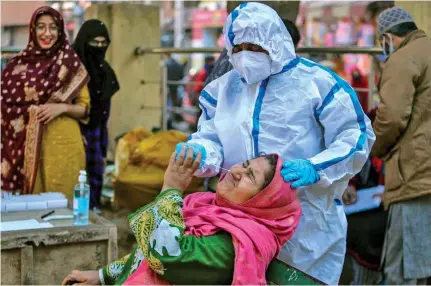  ?? ?? A health worker collects a swab sample of a woman to test for COVID-19 at a market in Jammu, India on December 29, 2021.