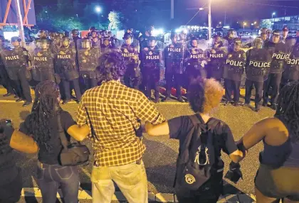  ?? JONATHON GRUENKE/STAFF ?? Hampton Police officers watch as protestors lock arms during a Black Lives Matter protest in Hampton Friday evening.