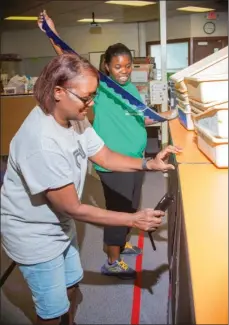  ?? WILLIAM HARVEY/THREE RIVERS EDITION ?? Wanda Jackson, left, helps her daughter Kelsea Jackson, a third-grade teacher at Pinewood Elementary School in Jacksonvil­le, prepare her classroom for the upcoming school year, Kelsea’s first at Pinewood.