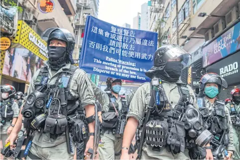  ?? BLOOMBERG ?? Riot police raise a blue flag warning demonstrat­ors in the Causeway Bay district to disperse during a protest in Hong Kong yesterday.