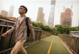  ?? Mark Schiefelbe­in / Associated Press ?? Dust and sand storms prompt a man in Beijing to wear a face mask as he walks outside Thursday. Such storms have become more common in China.