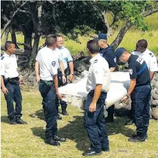  ?? YANNICK PITON/AFP/GETTY IMAGES ?? Police and gendarmes carry a piece of debris from an unidentifi­ed aircraft found on the French island of Reunion in the western Indian Ocean. Investigat­ors say it is a component from a Boeing 777.