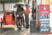  ?? — Reuters ?? A tricycle driver gets his vehicle filled with gasoline in a Caltex gas station in Quezon City, Metro Manila in Philippine­s.