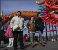  ?? (AP/Andy Wong) ?? People walk by a giant dragon lantern decorated near the frozen Houhai Lake in Beijing on Thursday.