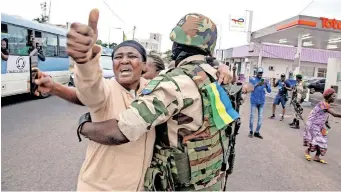  ?? | Reuters ?? A WOMAN embraces a soldier as she celebrates with people in support of a putschists, in a street of Port-gentil, Gabon, yesterday.