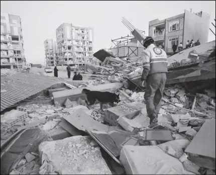  ?? POuRIA PAkIzEH/ISNA vIA AP ?? A rescue worker searches debris for survivors with his sniffing dog after an earthquake at the city of Sarpol-e-Zahab in western Iran.