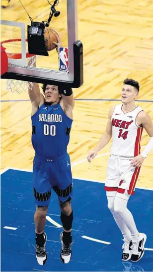  ?? ALEXMENEND­EZ/GETTY ?? The Magic’s Aaron Gordon dunks as the Heat’s Tyler Herro trails the play.