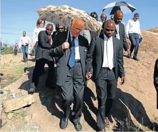  ?? Picture: LAUREN MULLIGAN ?? SITE VISIT: Commission chairman Judge Ian Farlam (with an umbrella) visits the scene of the Marikana shooting during which protesting miners were killed by the police