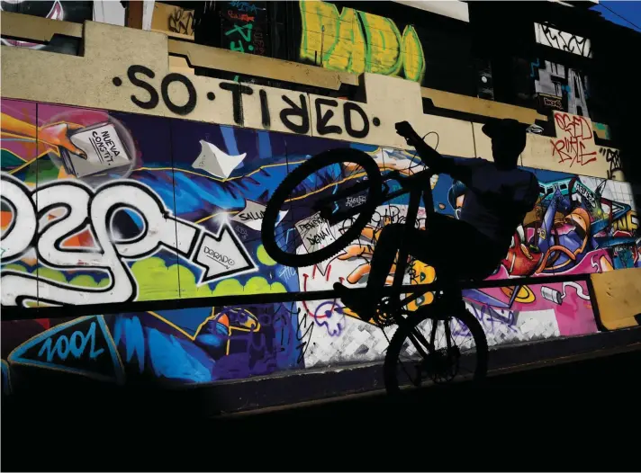  ?? ?? A man performs a wheelie on his bike through Paseo Bandera in Santiago, Chile. Photo: AP/Matias Delacroix