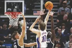  ?? ISAAC HALE/AP ?? KANSAS GUARD JOHNNY FURPHY (10) shoots over Gonzaga forwards Graham Ike (right) and Ben Gregg (left) during the first half of a second-round game in the NCAA Tournament in Salt Lake City on Saturday.