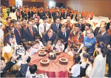  ??  ?? Ismail Sabri (centre), joined by children and others, cuts a cake to celebrate the 50th anniversar­y of Mara. Also seen is Nanta (second left). — Photo by Wilfred Pilo