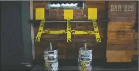  ??  ?? A bench made with kegs is taped off to prevent people from sitting at a bar temporaril­y closed.