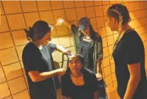  ??  ?? Members of Elevation drama team from North Cleveland Church of God in Cleveland, Tenn., prepare for their performanc­e. Cailyn Lennon, left, braids Miraina Patel’s hair as Jessie Baird holds a light. Catherine Fowler, right, looks on.