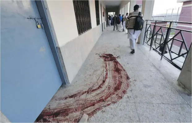  ?? AAMIR QURESHI / AFP / GETTY IMAGES ?? A student walks past a trail of blood following Wednesday’s terrorist attack on Pakistan’s Bacha Khan University, in Charsadda, about 35 kilometres outside of Peshawar. A Pakistani Taliban faction has claimed responsibi­lity for the assault, which claimed the lives of at least 20.