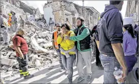  ?? ASSOCIATED PRESS ?? A woman is comforted as she walks through rubble after the earthquake in Amatrice, central Italy, Wednesday. A devastatin­g earthquake rocked central Italy early Wednesday, collapsing buildings on top of residents as they slept.