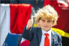  ?? Alexandra Wimley/Post-Gazette ?? Gino Benford, 7, of Johnstown, dressed as President Donald Trump, poses for photos Tuesday while in line to see Mr. Trump speak at a "Make America Great Again" rally at John Murtha Johnstown-Cambria County Airport in Johnstown.