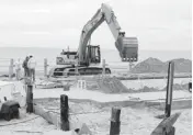  ?? AP PHOTOS ?? Work crews scoop sand Jan. 15 from a beachfront swimming pool in Sea Bright, N.J., as the cleanup from Superstorm Sandy continued.