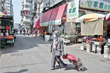  ?? AFP photo ?? A woman wears a face mask and a visor as she crosses a road in the Jordan area of the Yau Tsim Mong district of Kowloon in Hong Kong, an area of dense housing which has seen a recent spike in cases of the Covid-19 coronaviru­s. —