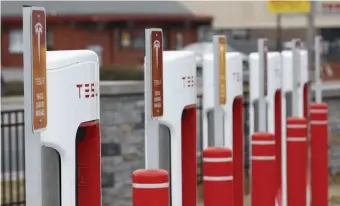  ?? BOSTOn HErAld FilE ?? AMBITIOUS GOALS: Tesla electric vehicle charging stations are seen in a gas station parking lot in Rhode Island.