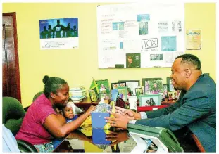  ??  ?? National Commercial Bank’s Senior Marketing Officer Roland Henry presents a tearful Natalee Cameron with $100,000 towards medication for her son Tahjae Stewart.