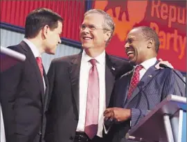  ?? Andrew Harnik ?? CANDIDATES Marco Rubio, Jeb Bush and Ben Carson, from left, chat on the debate stage during a break. Seven GOP hopefuls vied in an earlier debate.