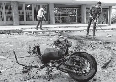  ?? REUTERS ?? A burnt motorbike is pictured as people clean up a street a day after gunfire erupted in an attack on protesters who were heading for a demonstrat­ion called by Hezbollah to demand the removal of the judge investigat­ing last year’s port explosion, in Beirut, Lebanon.