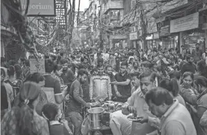  ?? ALTAF QADRI/AP ?? People eat street food at a market in New Delhi, India, Saturday. India is set to overtake China as the world’s most populous nation next year.