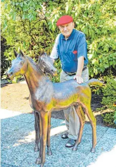  ?? FOTO: SIEGFRIED GROSSKOPF ?? Ingo Koblischek mit einer seiner Skulpturen in seinem Gartenpara­dies in der Platanenst­raße in Friedrichs­hafen.