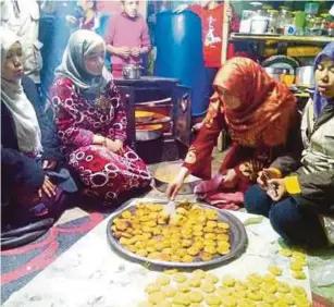  ??  ?? Sara (dua dari kanan) berkongsi biskut yang dibakarnya bersama-sama sukarelawa­n Aman Palestin yang mengunjung­i Kem Enma.