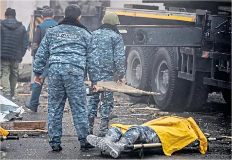  ??  ?? Armenian security forces remove the bodies of their comrades, above, from a cultural centre in Shushi after it was hit by an Azerbaijan­i missile; another device hit the dome of the Holy Saviour cathedral, right, in Shushi yesterday