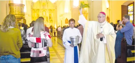  ??  ?? Monseñor Edmundo Valenzuela procede a la bendición de los feligreses con el agua bendita pascual ayer en la Catedral.