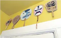  ??  ?? A curry-yellow powder room displays fans from the owner’s travels. The owner loves to collect pieces from travels, different cultures and artists. “I’m an inveterate collector of people, shapes, fans, spoons, hats — shapes that repeat themselves,” she says.