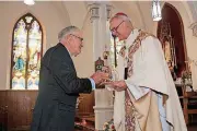  ?? [PHOTOS PROVIDED BY ARCHDIOCES­E ?? Tom Rother, brother of the Rev. Stanley Rother, hands a reliquary containing a relic of Stanley Rother to the Most Rev. Paul Coakley, archbishop of the Archdioces­e of Oklahoma City, during an Oct. 15 Mass at Holy Trinity Catholic Church in Okarche.