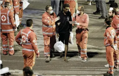  ?? PICTURE: REUTERS ?? GREENER PASTURES?: A migrant is helped by Red Cross members after disembarki­ng from Italian coastguard vessel “Diciotti” at the port of Catania, Italy, on Monday.