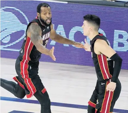  ?? ASHLEY LANDIS/AP ?? Andre Iguodala, left, celebrates with Tyler Herro during second half of the Heat’s playoff victory against the Pacers in Lake Buena Vista.