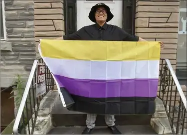  ?? BEN HASTY - MEDIANEWS GROUP ?? Kathiria “Ezra” Zorrilla posses holding a nonbinary flag in front of their home on Franklin Street in Reading. Zorrilla identifies as nonbinary gendered and uses the pronouns they, them and theirs.