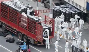  ?? (AP/Chinatopix) ?? Workers in personal protective equipment unload groceries from a truck Tuesday before distributi­ng them to local residents under the covid-19 lockdown in Shanghai.