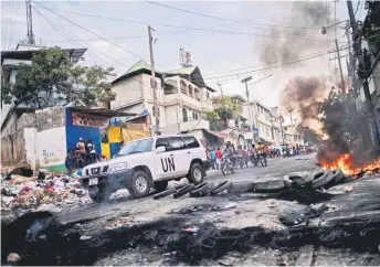  ?? — AFP photo ?? A United Nations vehicle drives past a barricade of burning tires during a demonstrat­ion against high prices and fuel shortages in Port-au-Prince.