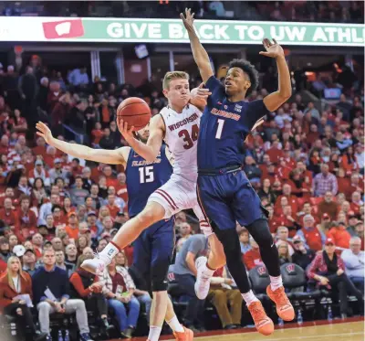  ?? ASSOCIATED PRESS ?? Wisconsin’s Brad Davison passes around Illinois’ Trent Frazier (right) as Giorgi Bezhanishv­ili (15) looks on during the Badgers’ 64-58 victory Monday night. Davison led UW with 18 points.