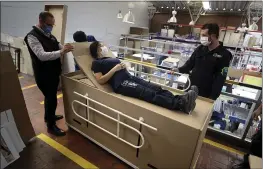  ?? PHOTOS BY FERNANDO VERGARA — THE ASSOCIATED PRESS ?? Rodolfo Gomez, left, and his employees demonstrat­e how their design of a cardboard box can serve as both a hospital bed, above, and a coffin, photo below.