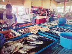  ??  ?? PENIAGA Pasar Basah Bandar Baru Bangi menimbang ikan pelanggan.