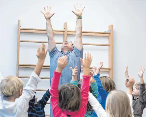  ?? FOTO: DPA ?? Die Arme in die Luft, sich groß machen und stark fühlen: Persönlich­keitstrain­er Jürgen Rüstow zeigt den Kindern in der Berliner Kindertage­sstätte Wolkenzwer­ge eine Übung.