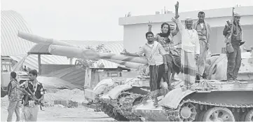  ??  ?? Members of a coalition of fighters made up of local tribes, Popular Resistance Committees and supporters of the southern Yemeni separatist movement, who are all opposing the Shiite-Huthi movement, flash the sign for victory as they stand on a tank at...