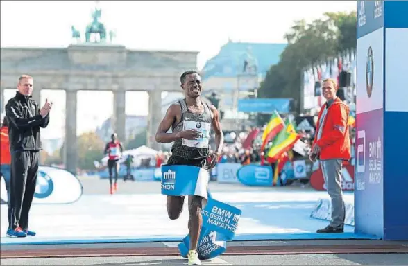  ?? RONNY HARTMANN / GETTY ?? Kenenisa Bekele cruza la meta, en la puerta de Brandembur­go, ayer; al fondo, su perseguido­r, Wilson Kipsang