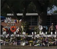  ?? (AP/Jae C. Hong) ?? Flowers and candles are placed around crosses in May at a memorial outside Robb Elementary School in Uvalde, Texas, to honor the 21 victims killed in the school shooting a few days prior.