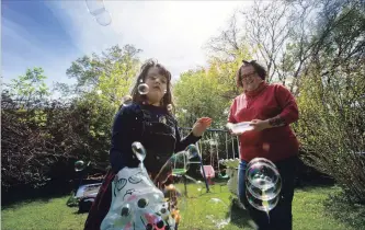  ?? JULIE JOCSAK THE ST. CATHARINES STANDARD ?? Tricia Sauve and her daughter Ellie Sauve play with bubbles at their St. Catharines home on Friday.