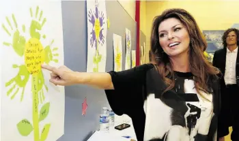 ?? CHRISTINA RYAN/POSTMEDIA NEWS ?? Shania Twain admires children’s art during a visit to a Calgary school this week.